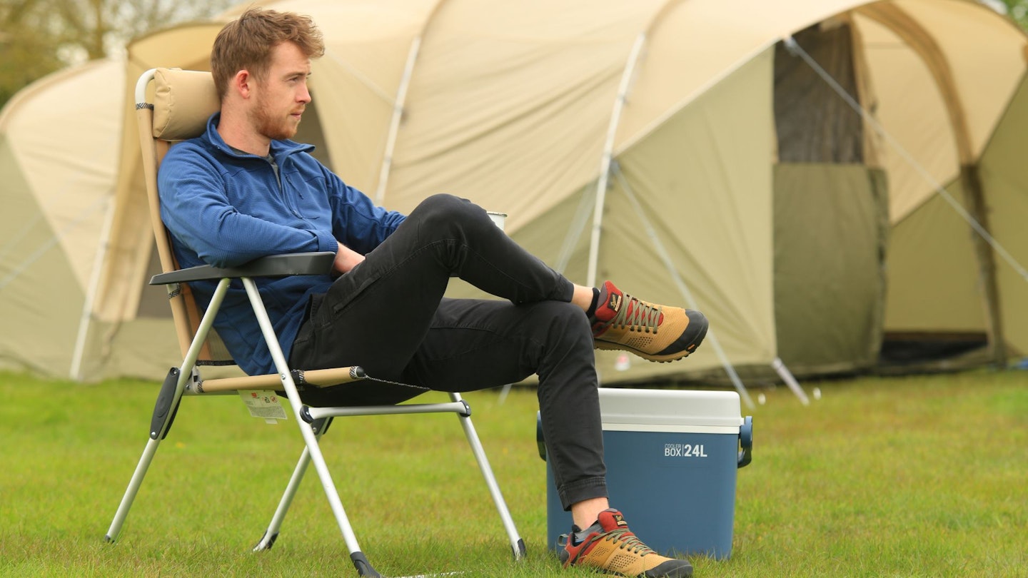 Camper, camping chair and cool box on campsite