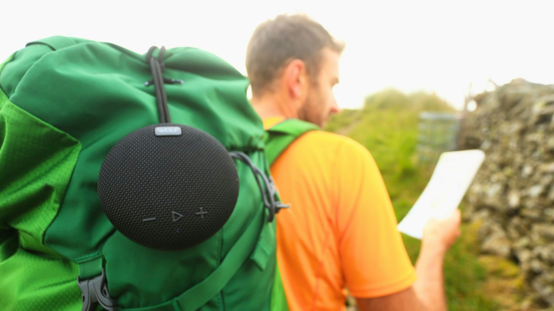 Hiker carrying a cluetooth camping speaker on a backpack