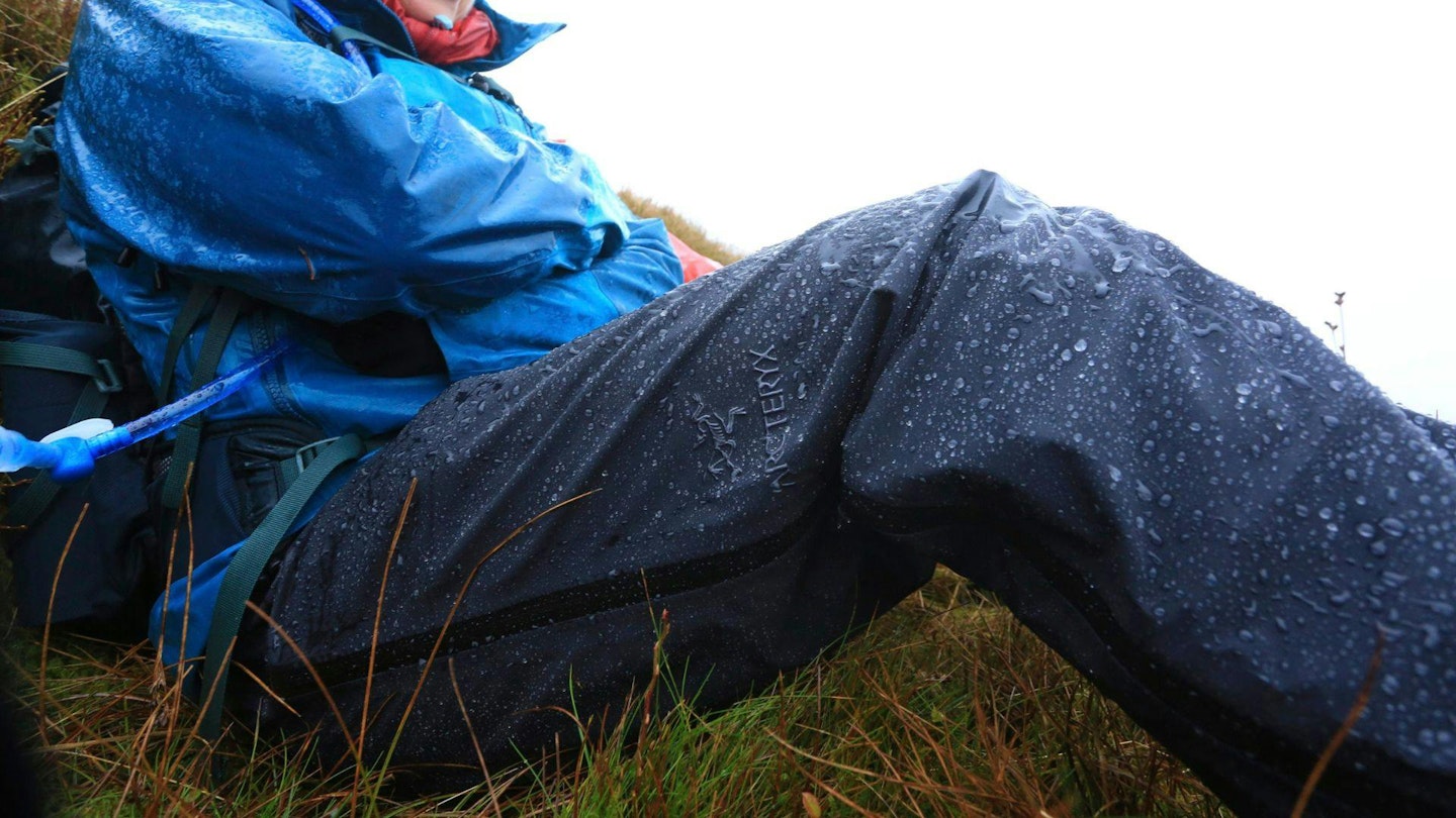 Hiker sitting down wearing waterproof trousers on a rainy hillside