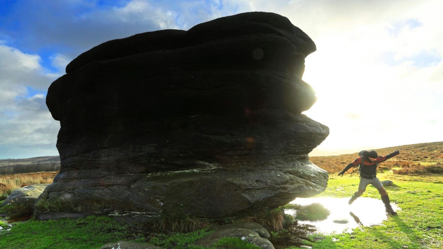 Hiker at Eagle stone near Baslow Edge in the Peak District