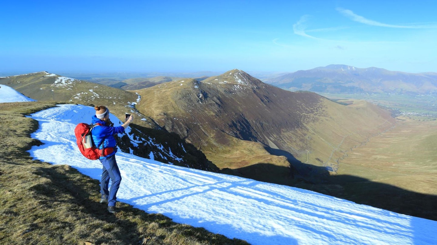 Hiker on summit of Crag Hill looking down to Cole Dale Lake District