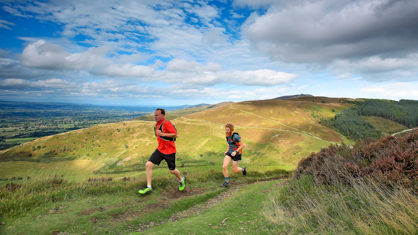 Trail runners heading up a grassy hill