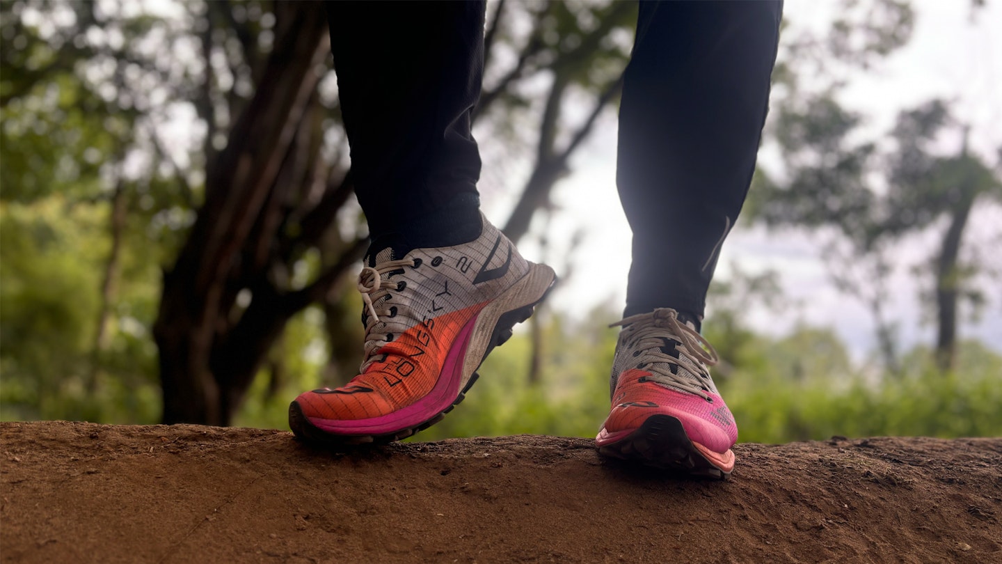 Standing on a dirt hill wearing the MTL Longsky 2 trail running shoes