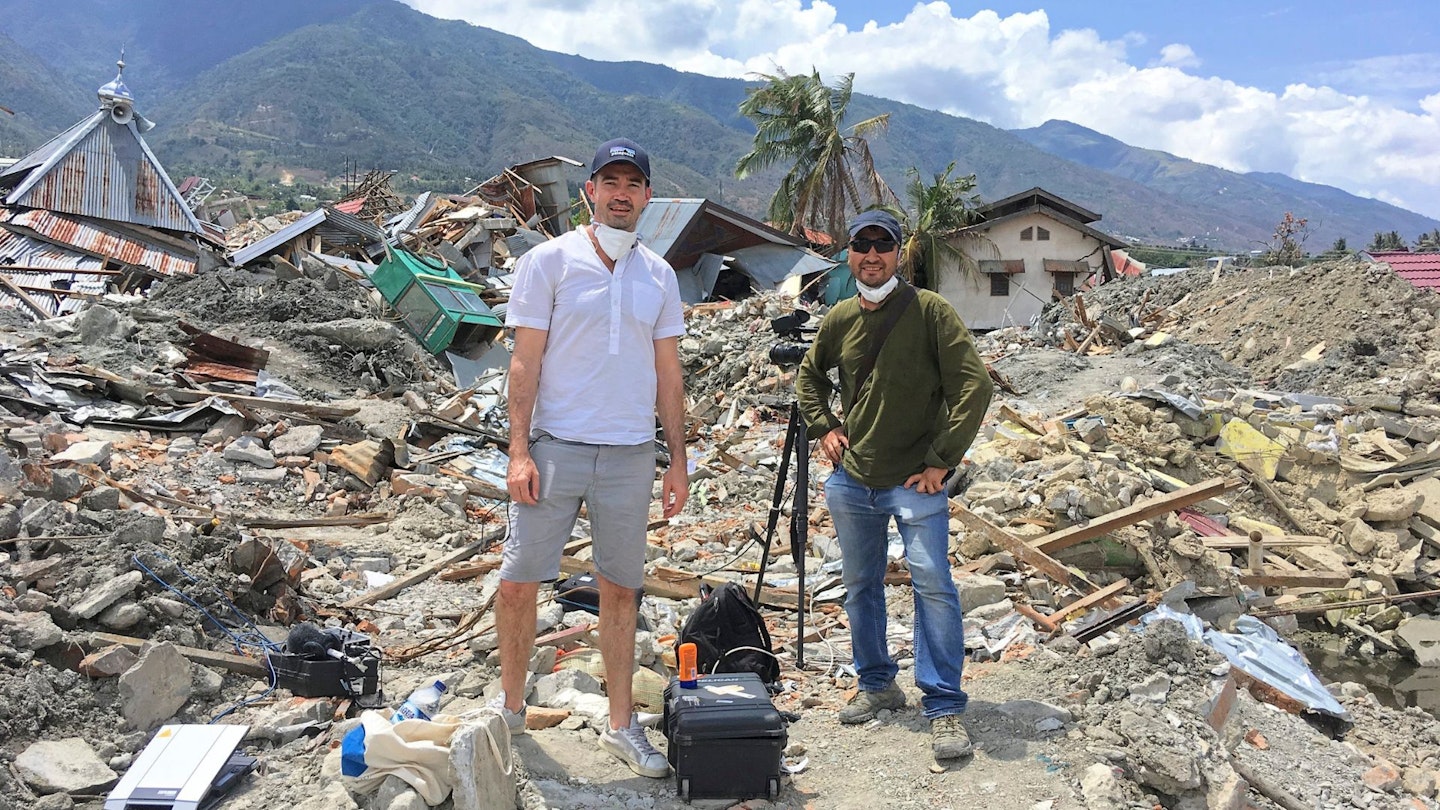 Howard Johnson standing in front of rubble after a tsunami