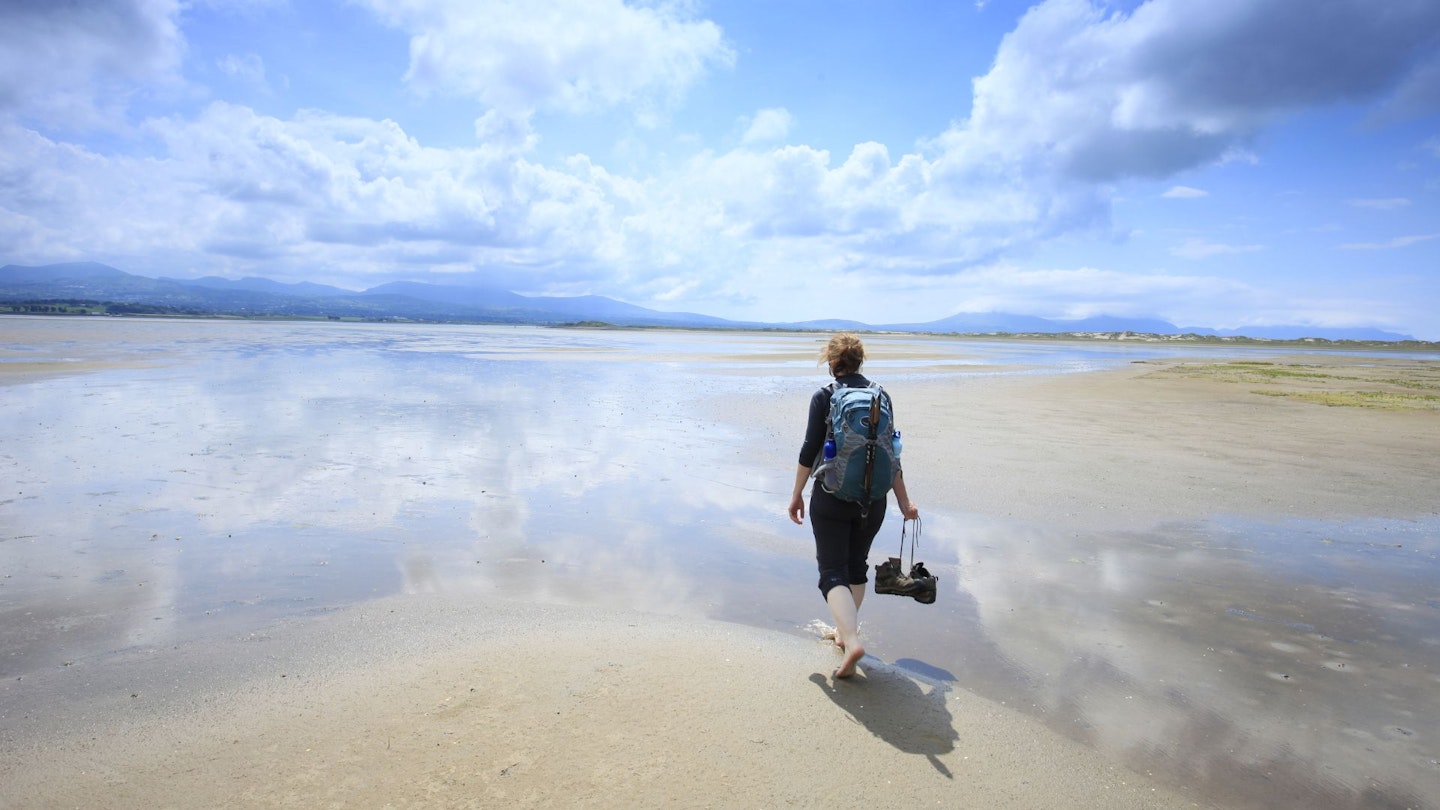 Woman walks along a flat sandy beach at low tide