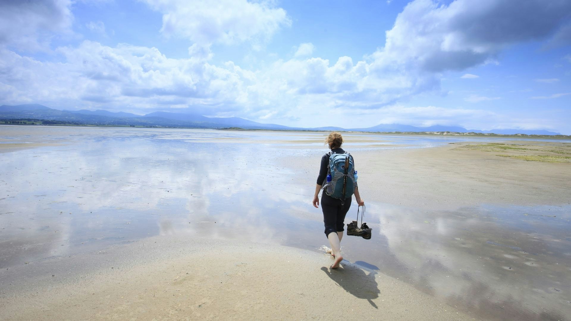 Woman walks along a flat sandy beach at low tide