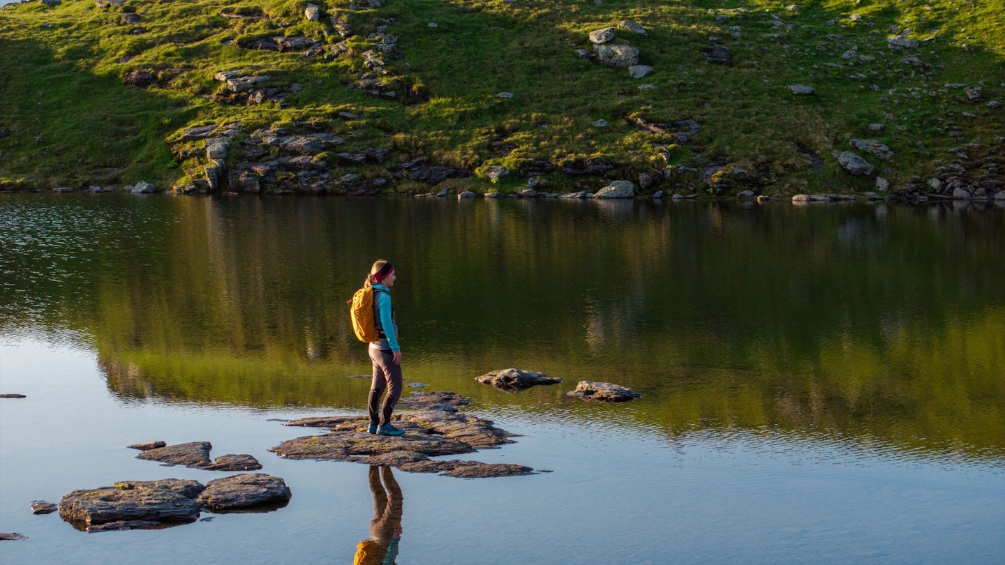 Woman stands in the middle of a river with an exped skyline backpack