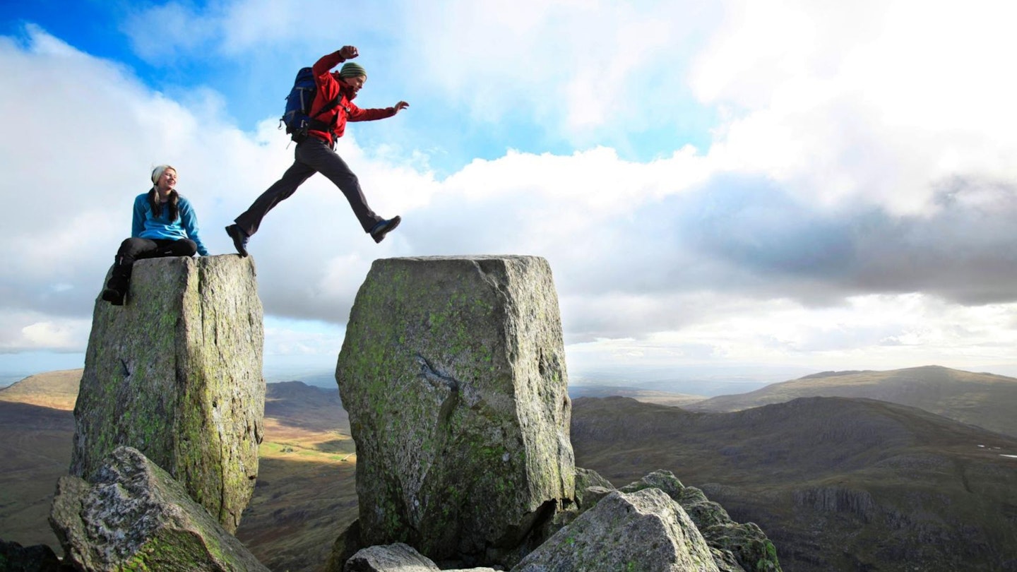 Hiker jumping Adam and Eve stones, Tryfan, Snowdonia