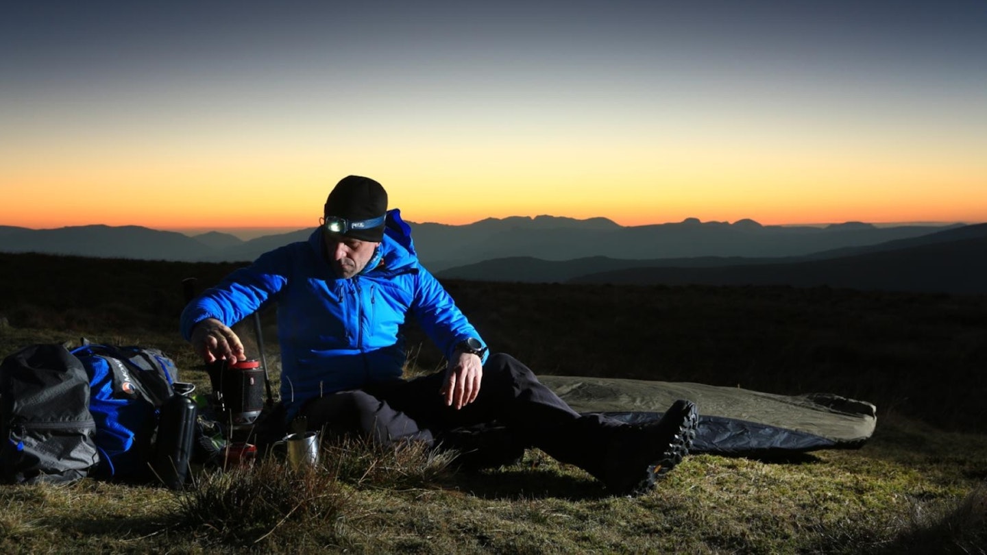 Hiker with a backpacking stove while bivvying in the Lake District