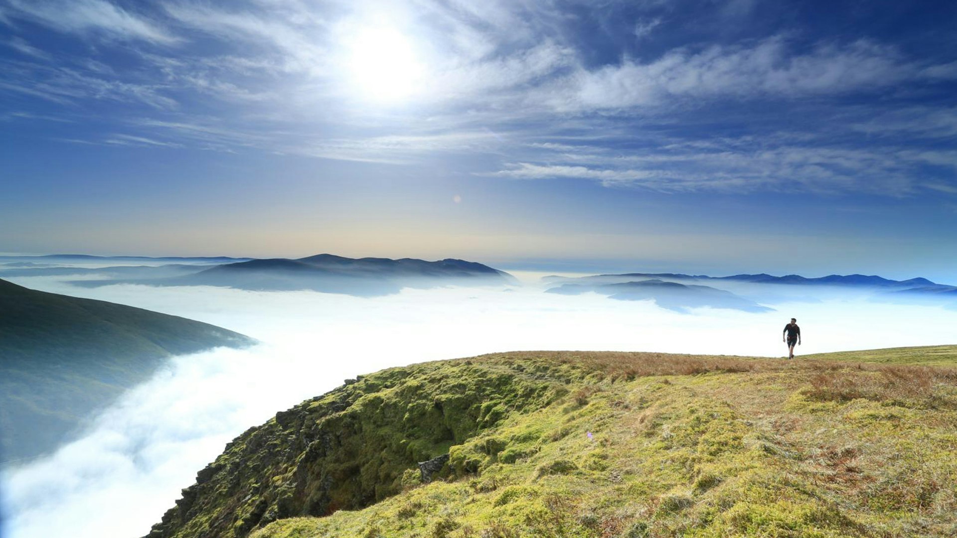 Walking over grassy mountains above clouds