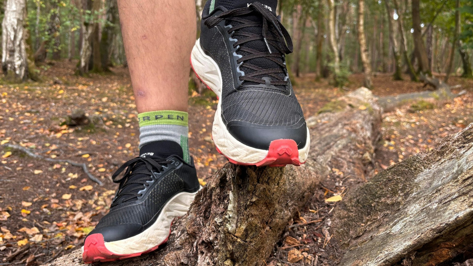 standing on a log in the Nnormal Kjerag 02 trail running shoe