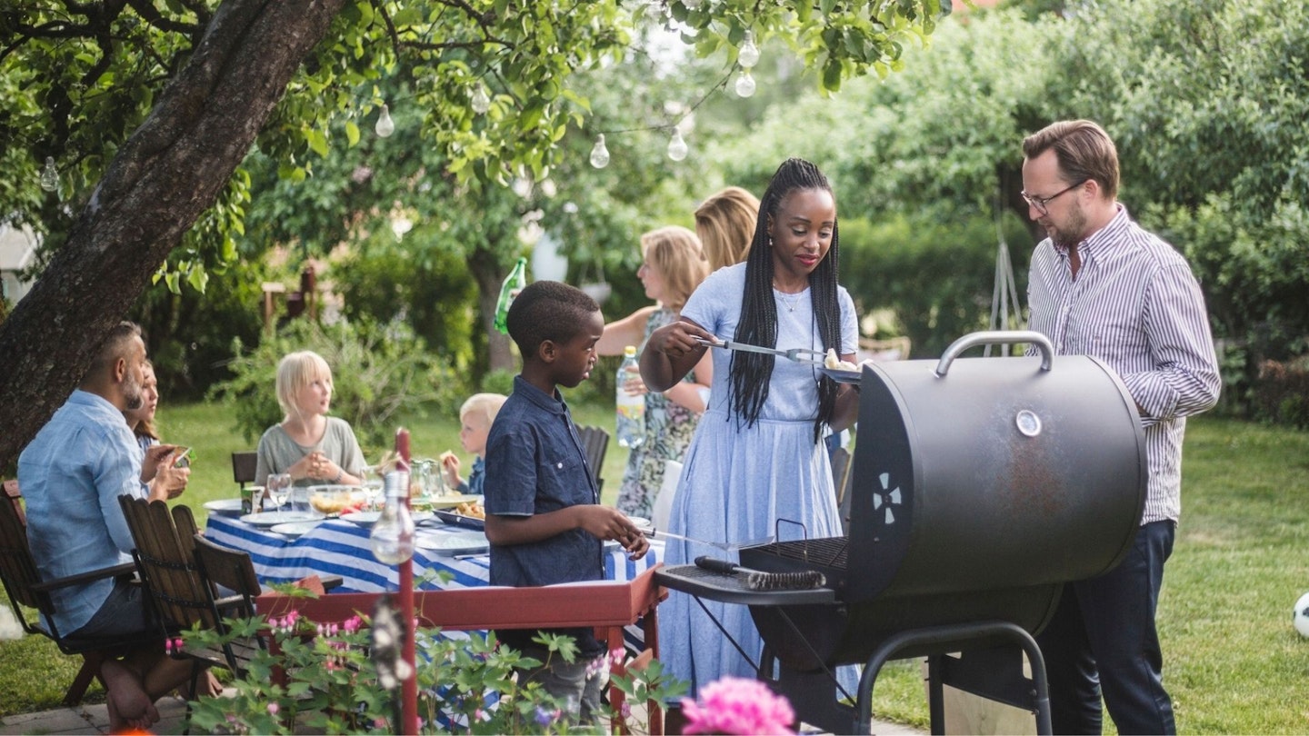 Man talking to woman with son preparing food at barbecue grill BBQ fuel
