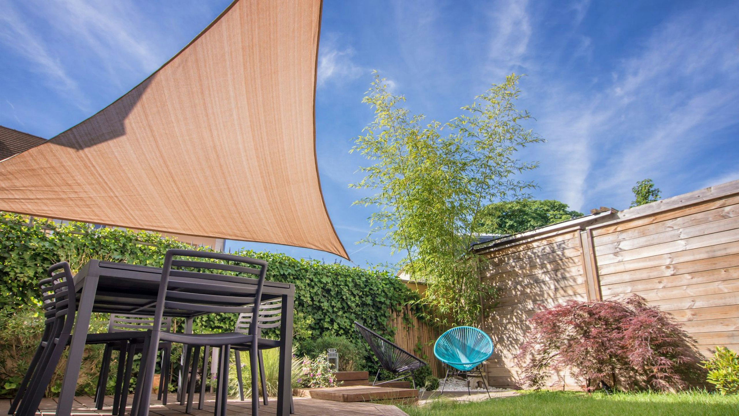 Modern house terrace in summer with table and sail shades