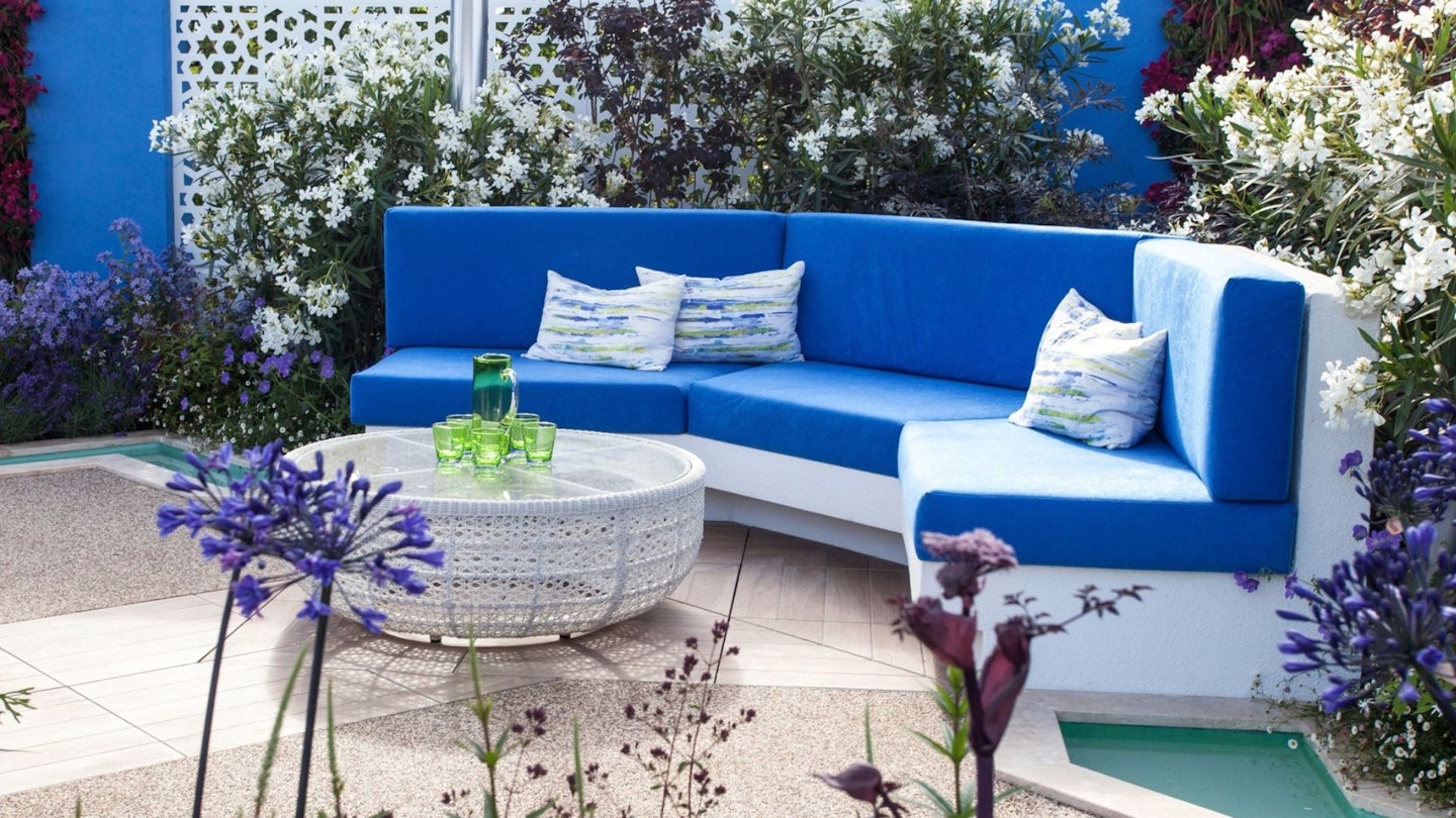 Bright blue seat pads and cushions on a garden bench in a modern garden.