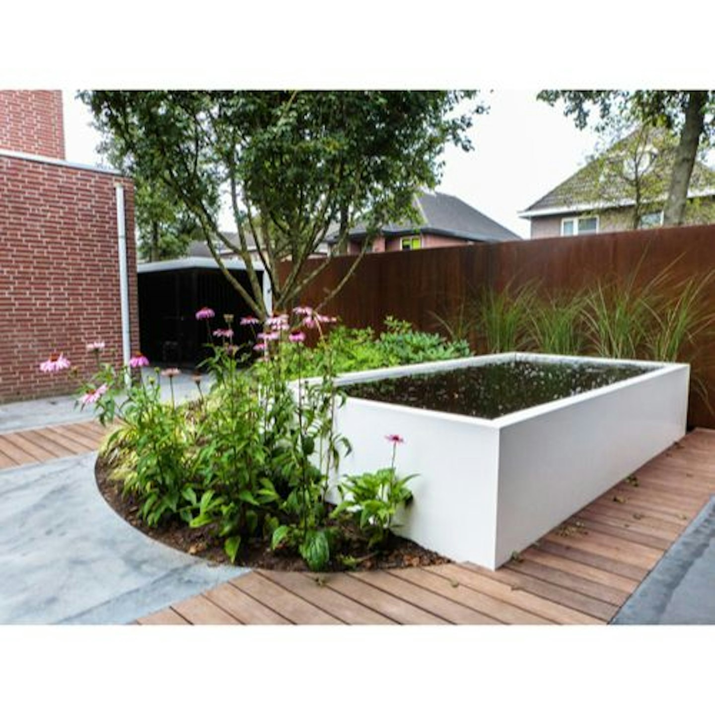 white aluminium raised pond set into pink flowers and wooden decking