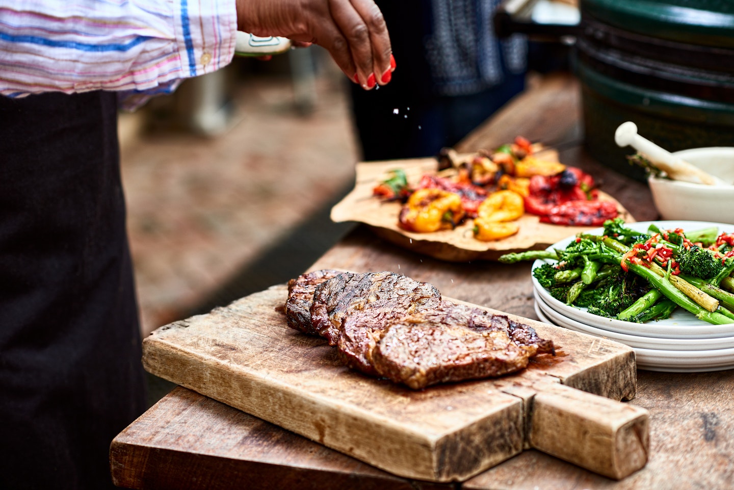 Woman sprinkling salt on freshly cooked steak