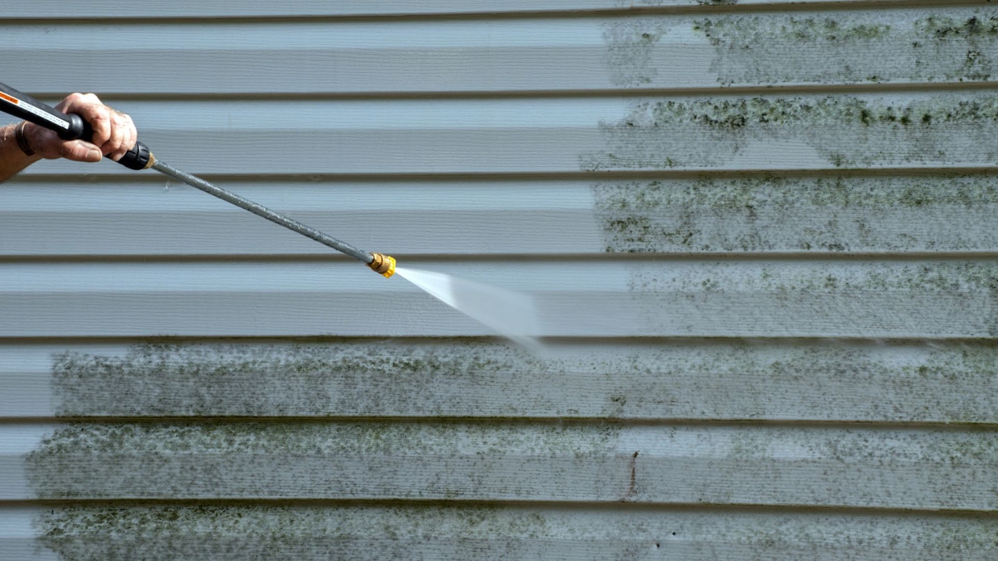 Pressure washer cleaning wall