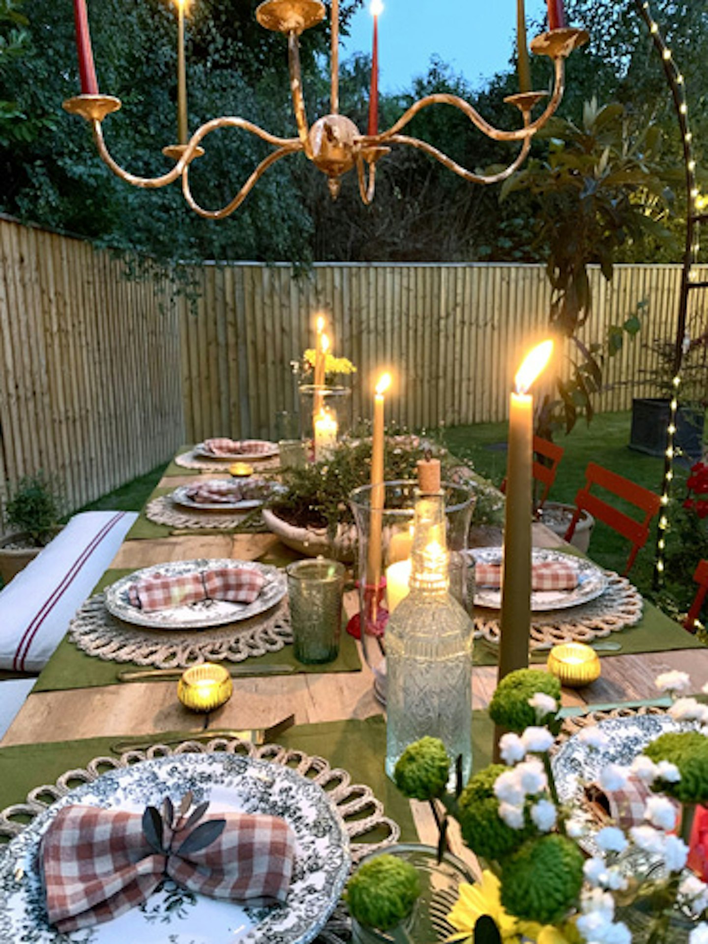 garden dining table lit by candles at night