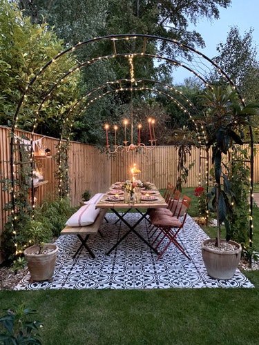 garden dining table lit up with overhead fairylights