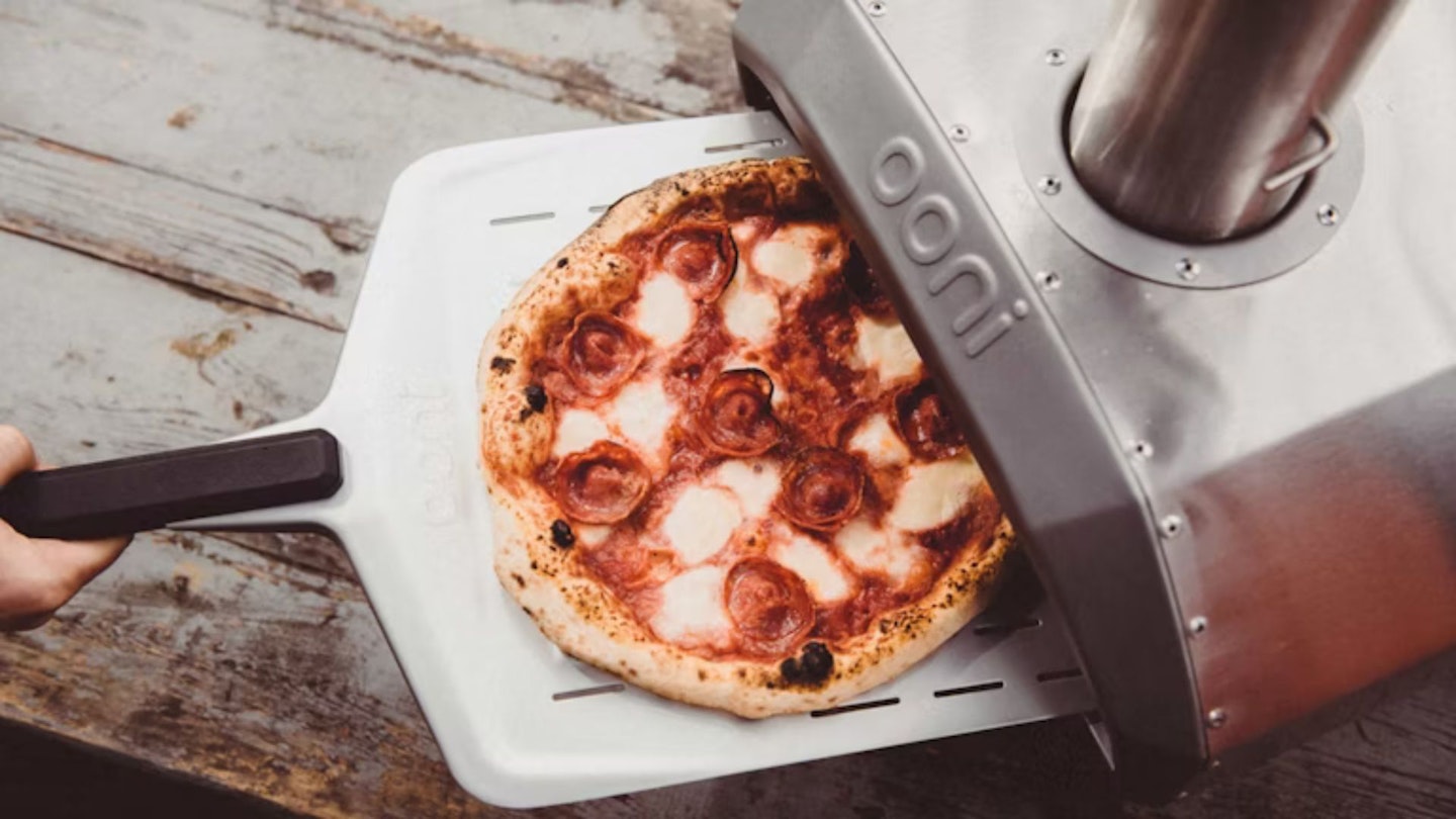 A cooked pizza emerging from an Ooni pizza oven