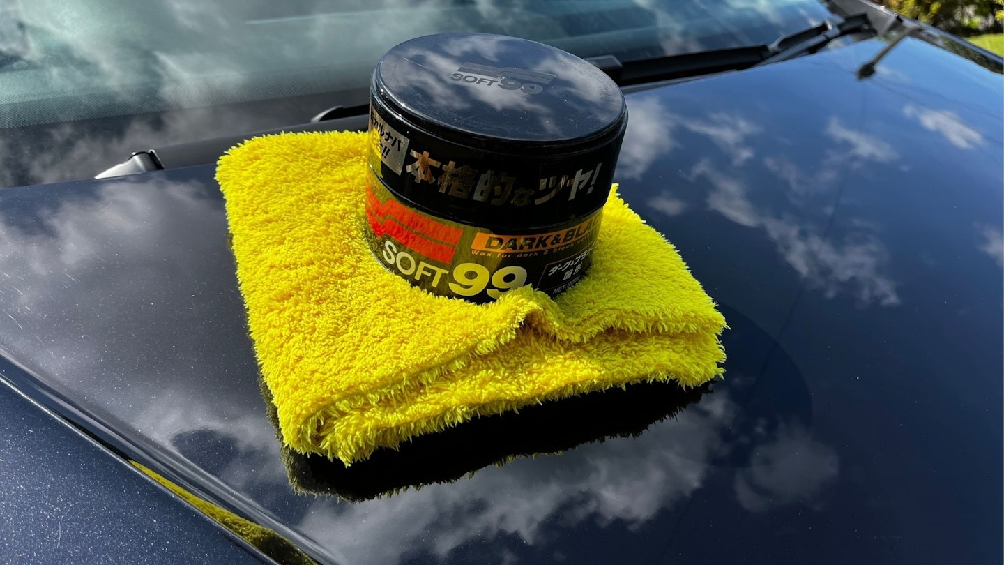 The tin of Soft99 Black and Dark Car Wax resting on a car bonnet
