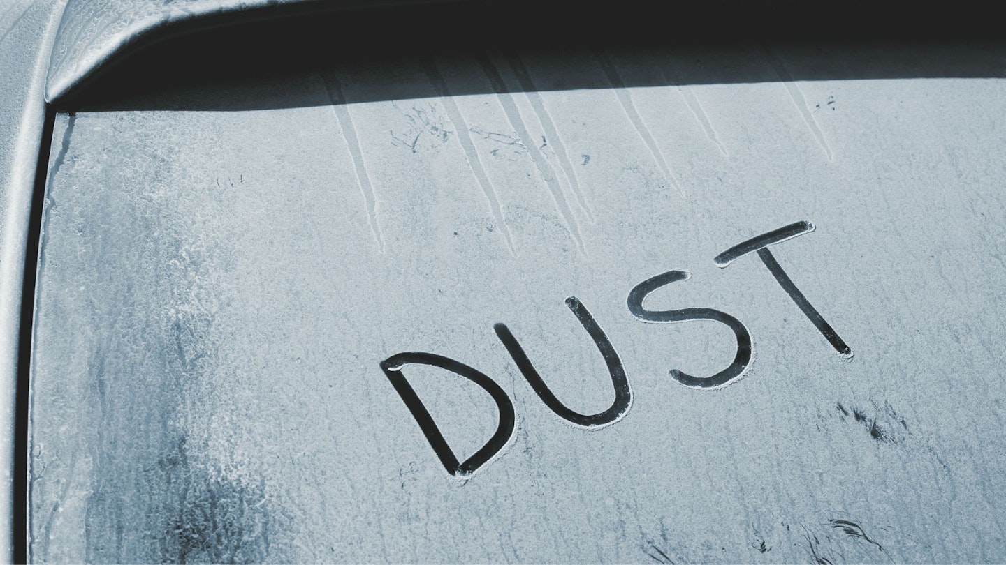 A dirty car with 'dust' inscribed in it