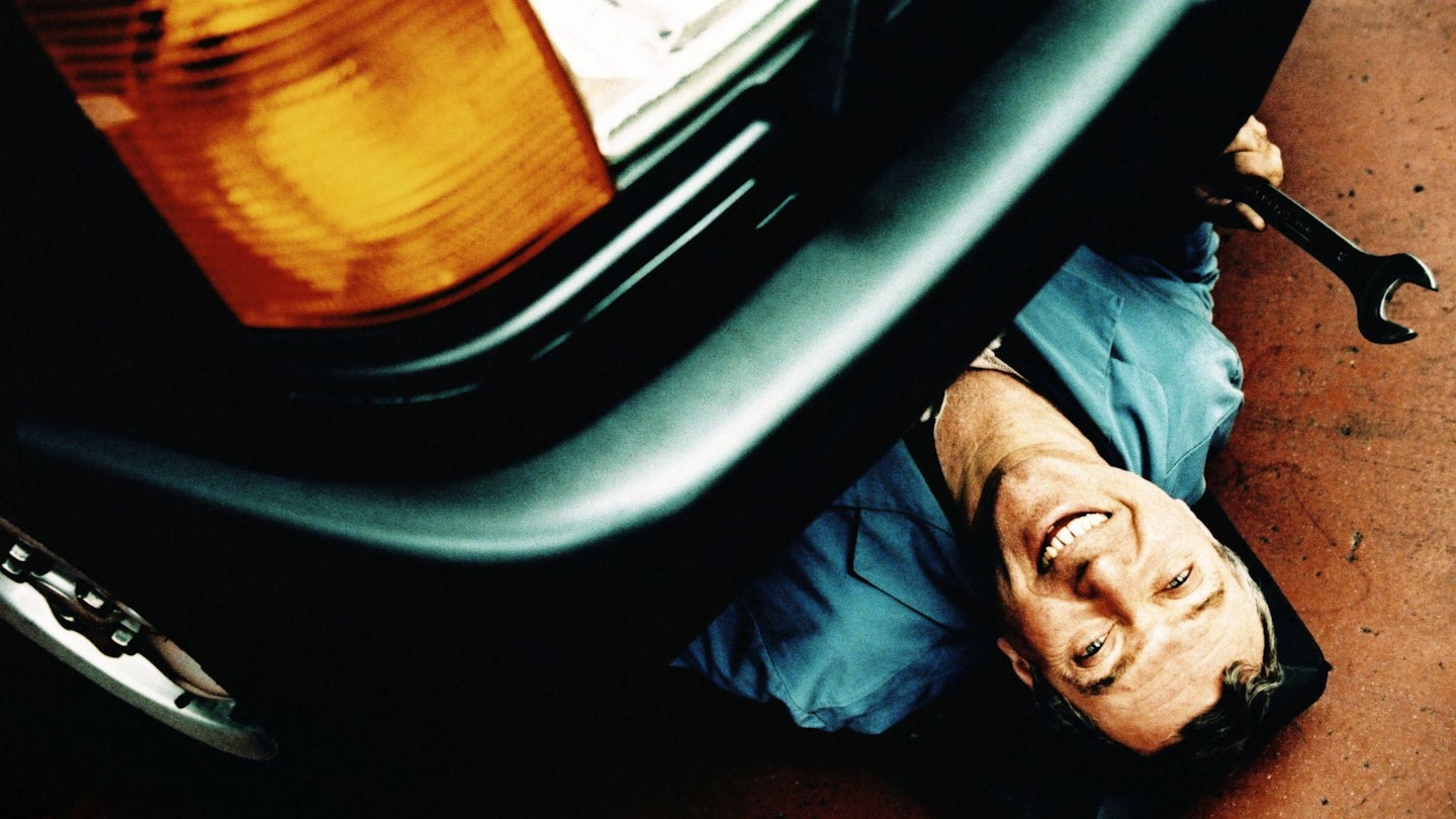 A mechanic lays underneath a car