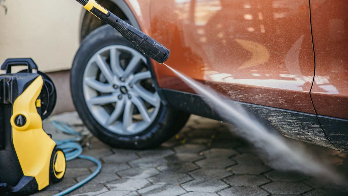 A pressure washer being used on a car