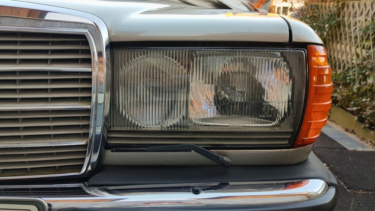A close-up shot of the halogen headlights of a Mercedes W123