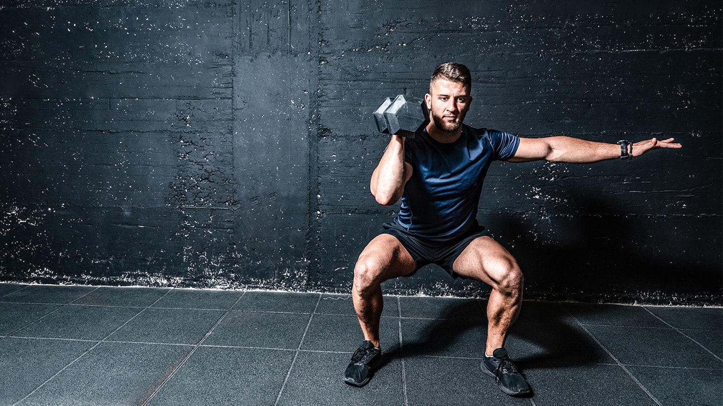 Man squatting with dumbbell