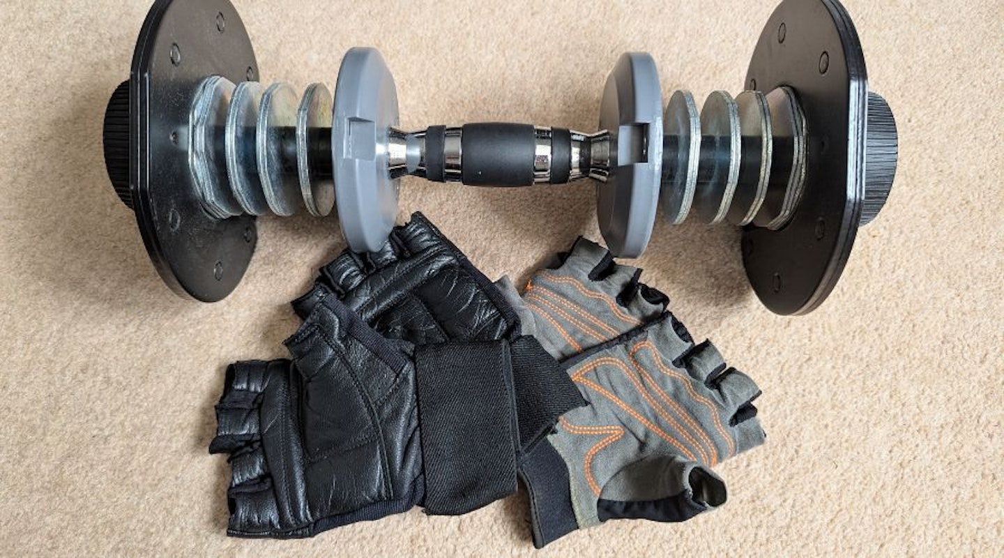 Weightlifting gloves in front of an adjustable dumbbell