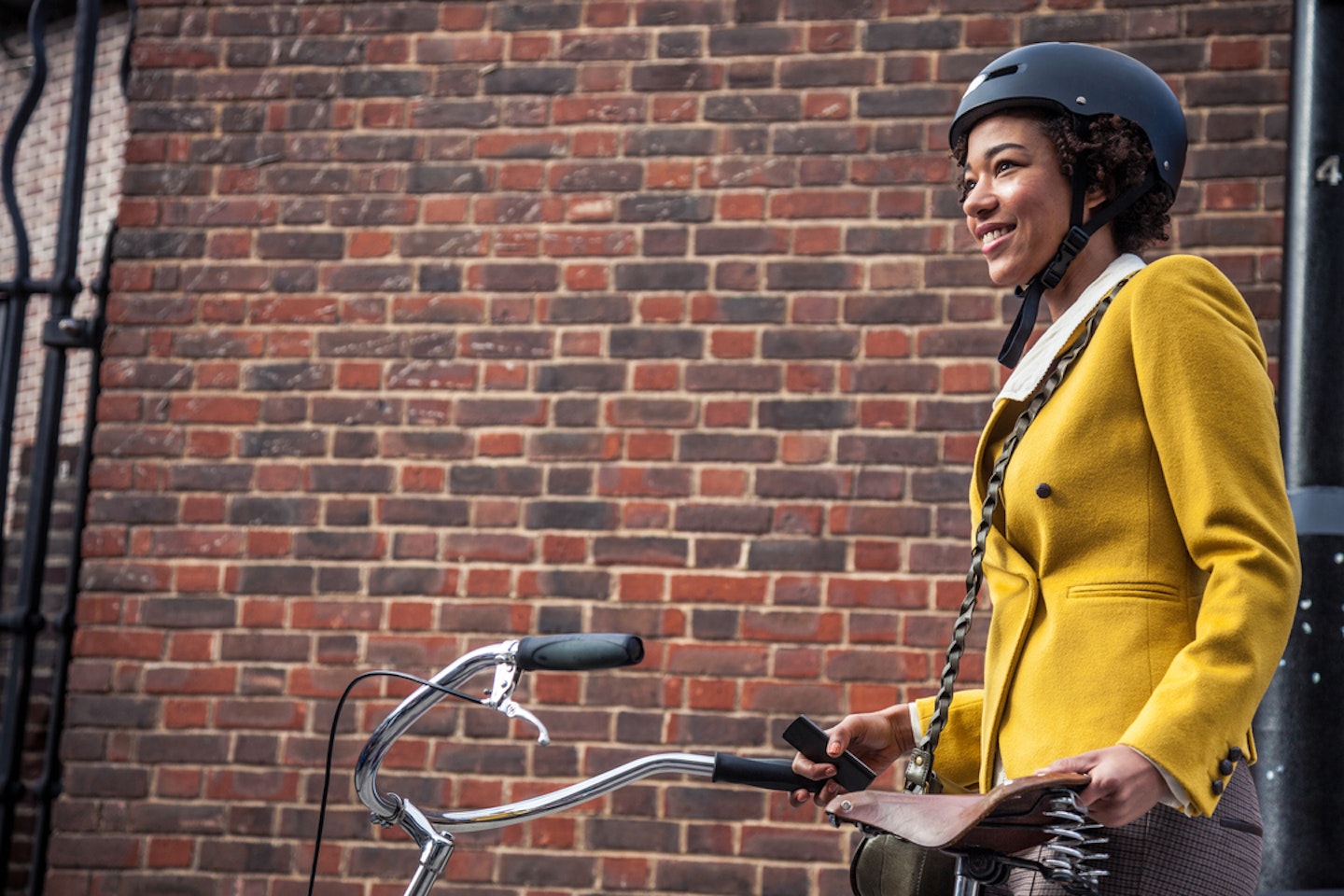 A woman wearing one of the best commuter cycling helmets against a brick wall