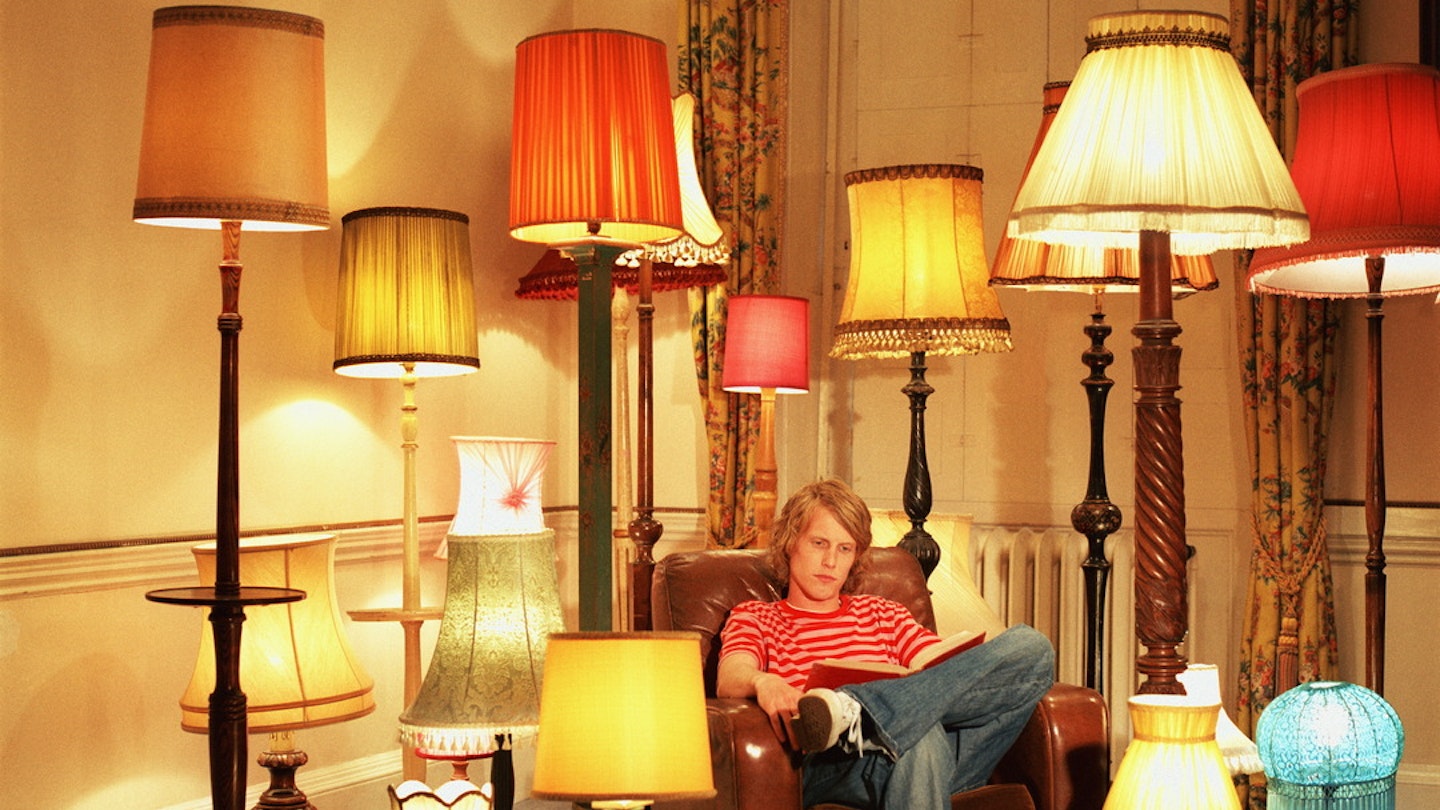 Man reading a book with many lamps