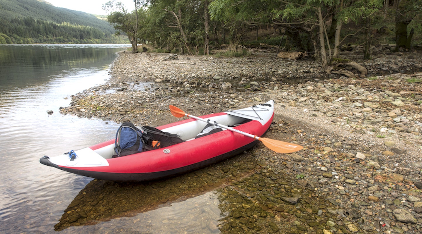 one-person inflatable kayak by a river bank
