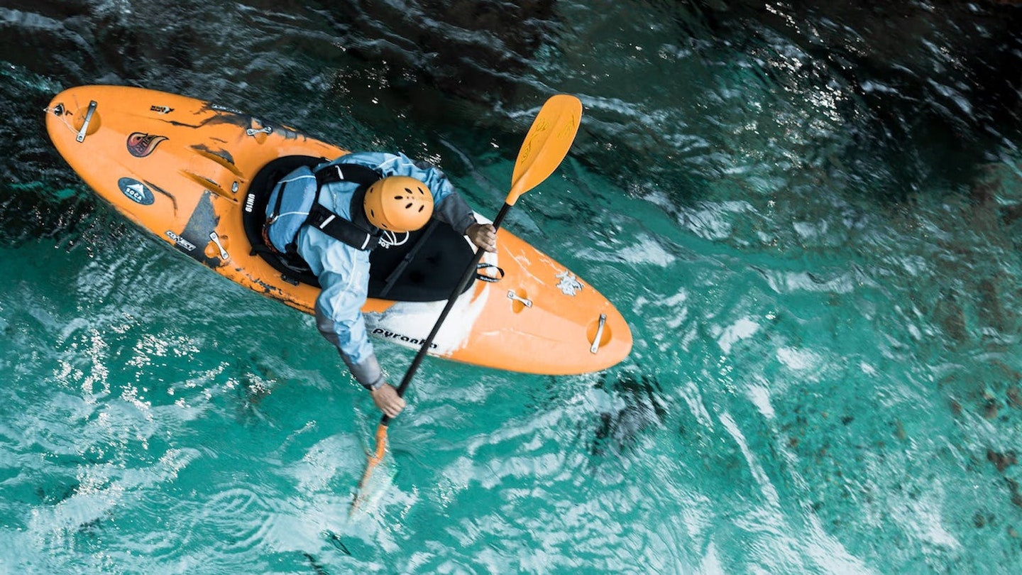 Orange kayak going over blue water