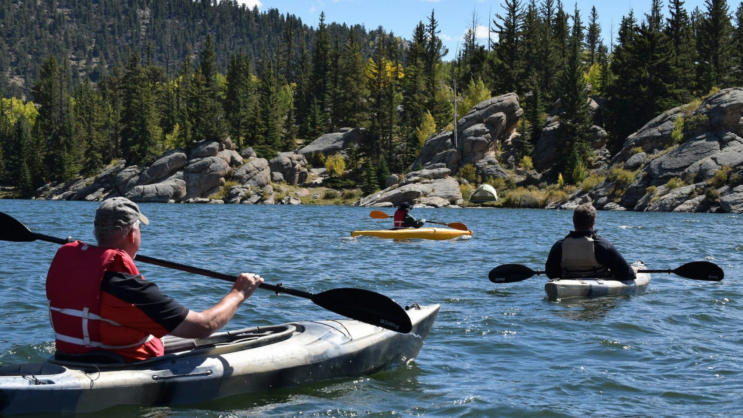 People in kayaks on a lake, wearing the correct clothing