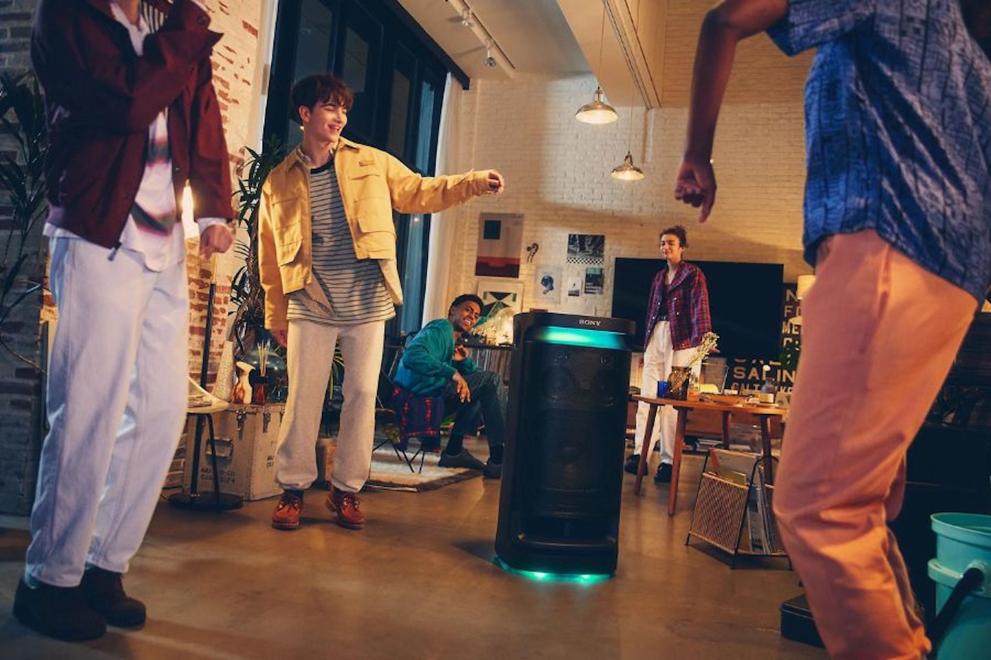 A group of young adults gathered around Sony's SRS-XV900 party speaker