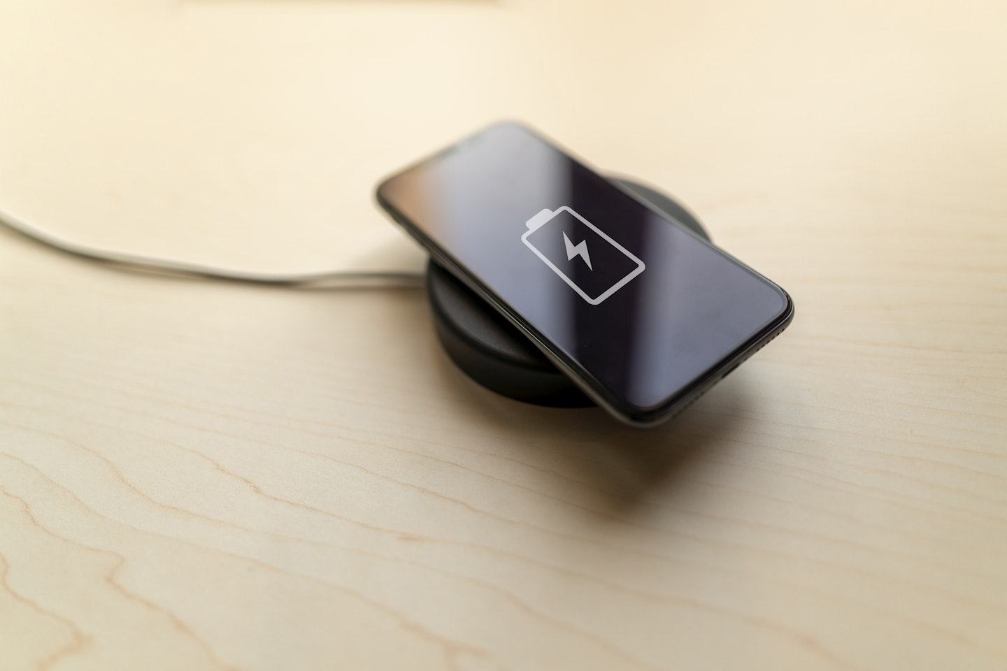 Charging mobile phone with wireless charging device on a wooden table