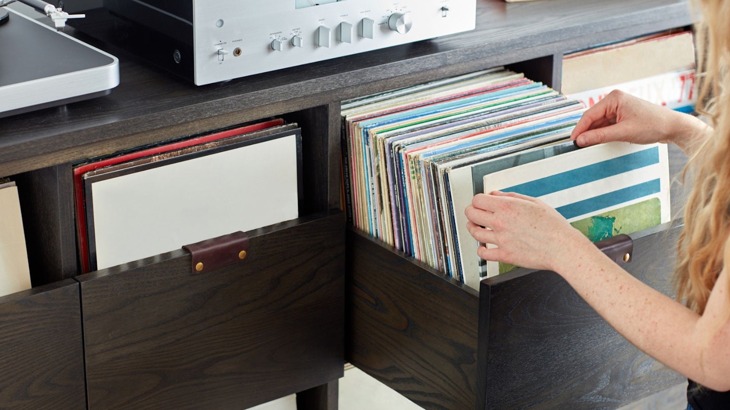Best vinyl record storage - Woman sifting through vinyl record collection in custom cabinet - stock photo