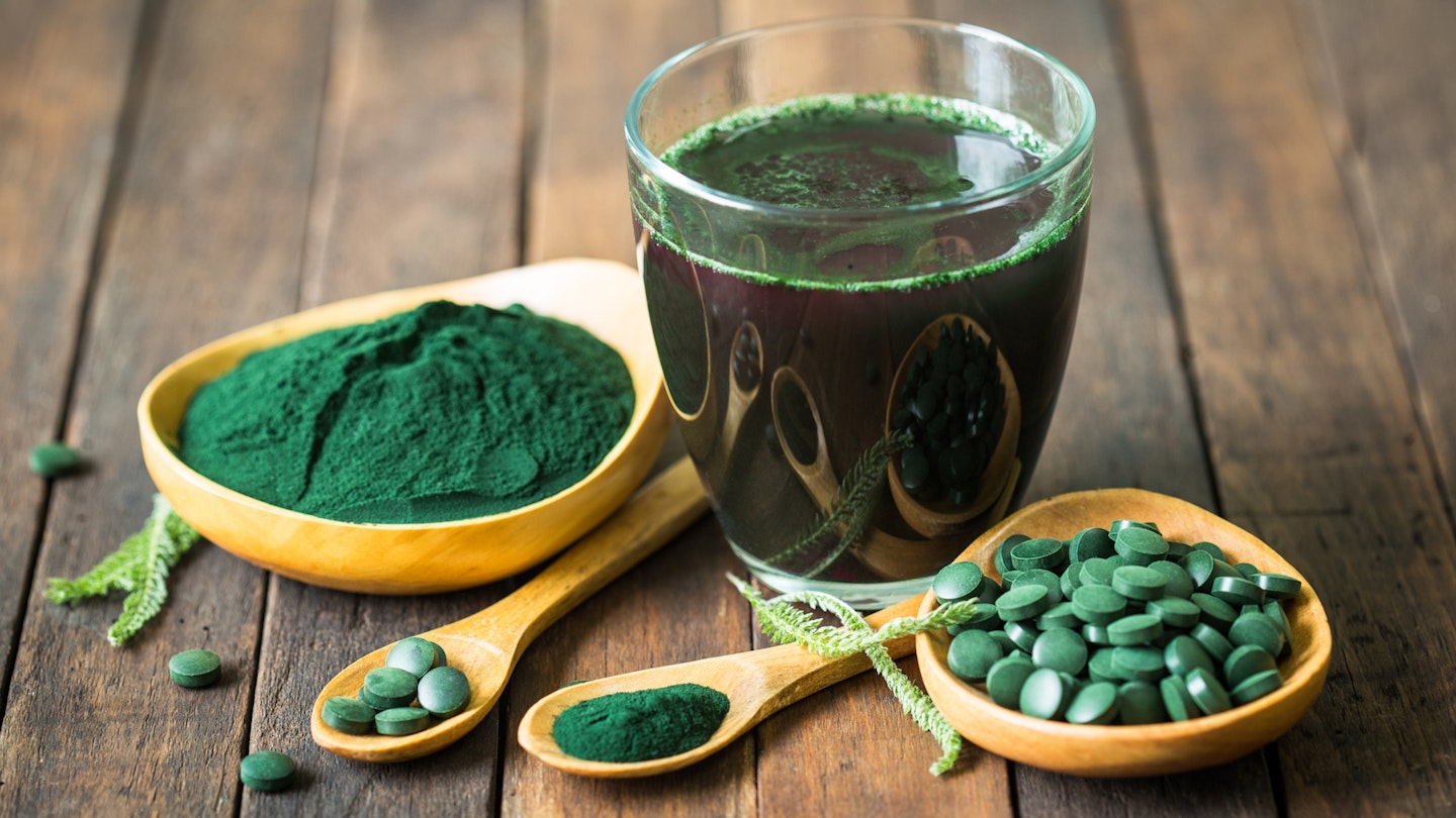 spirulina supplements: tablets and powders on a spoon and glass