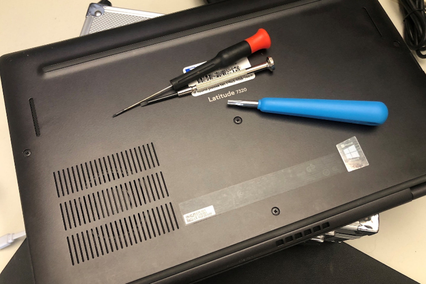 a dell latitude laptop upside down with screwdrivers