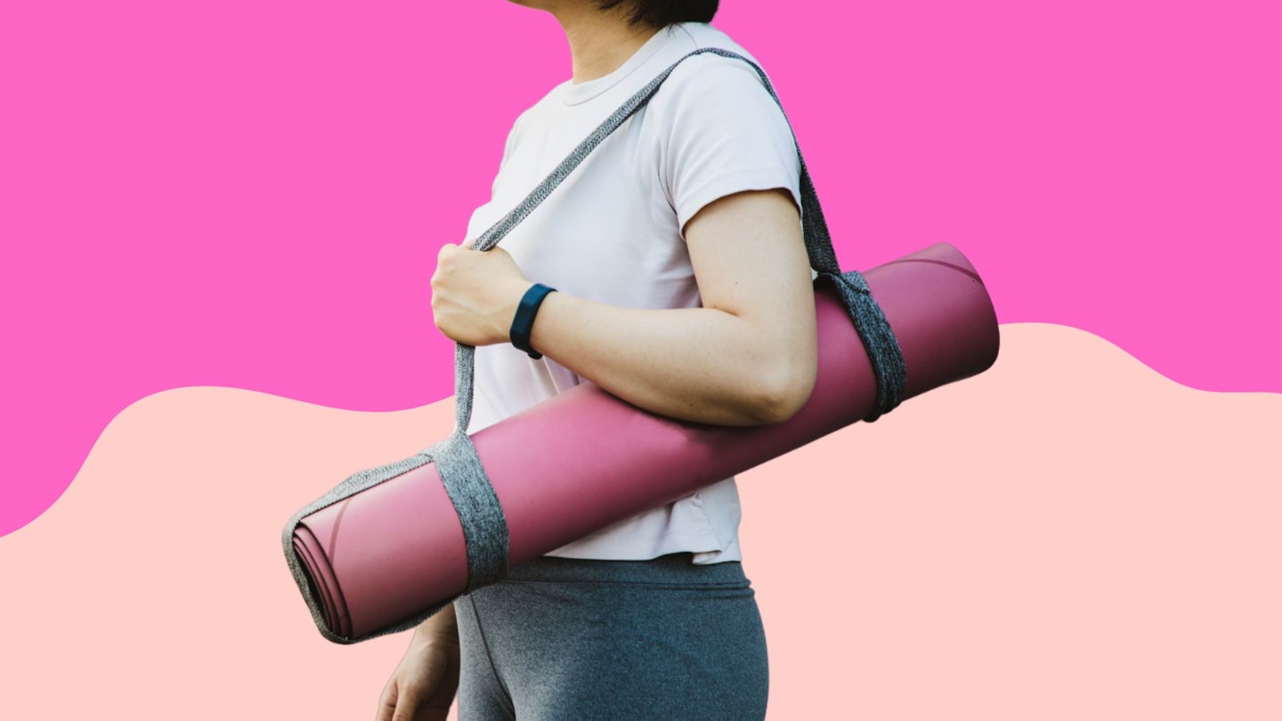 A woman holding one of the best yoga mats on a pink background.