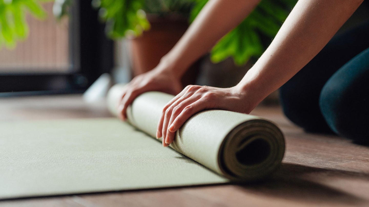Close up of a young woman unfolding one of the best Pilates mats