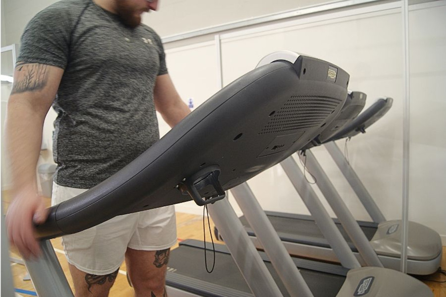 A man dressed in grey using a treadmill in a gym