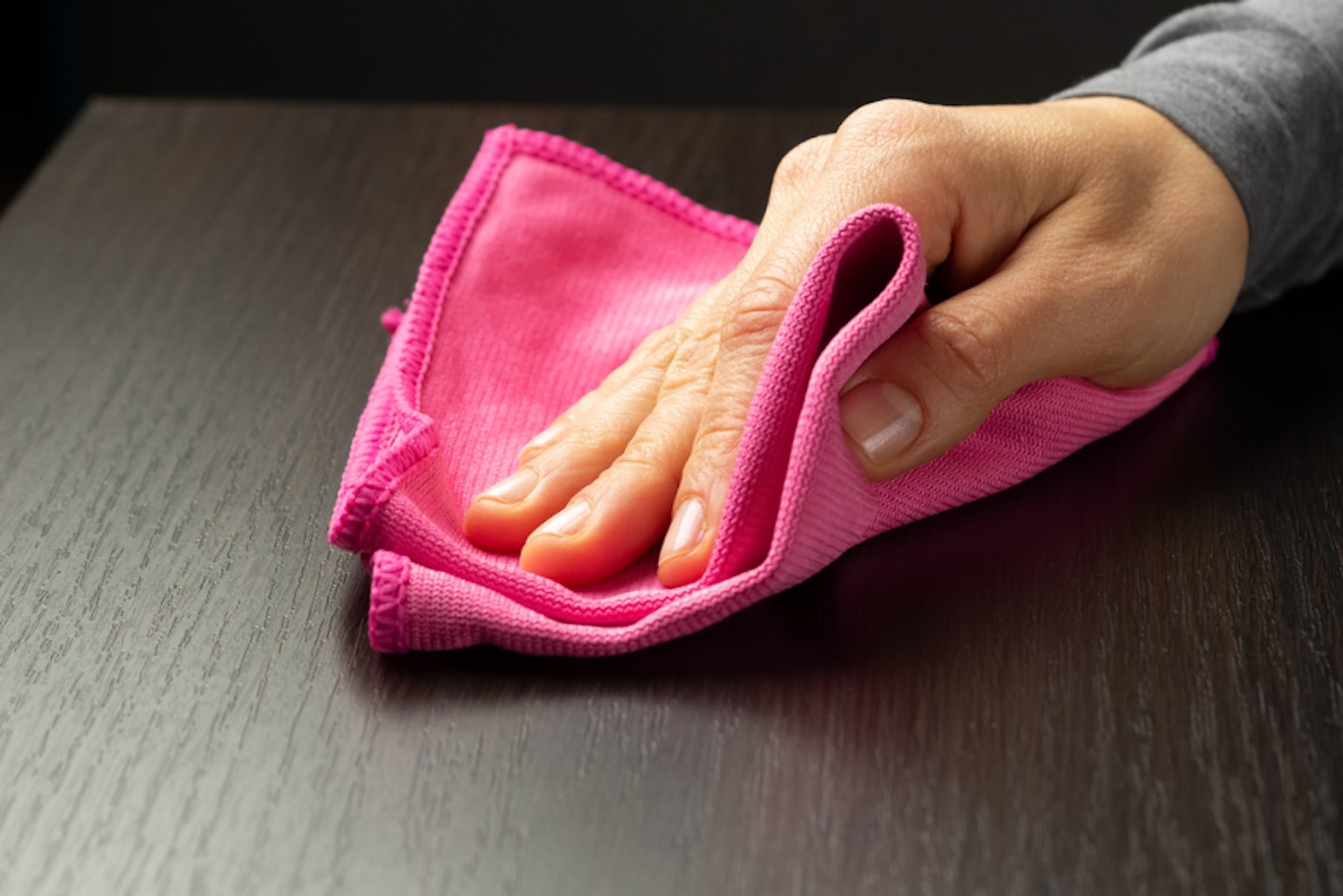 A HAND CLEANING A WOODEN SPEAKER