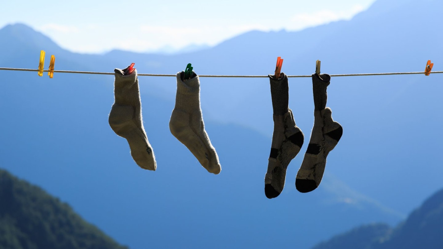Two pairs of the best walking socks hanging from a washing line with mountains in the background