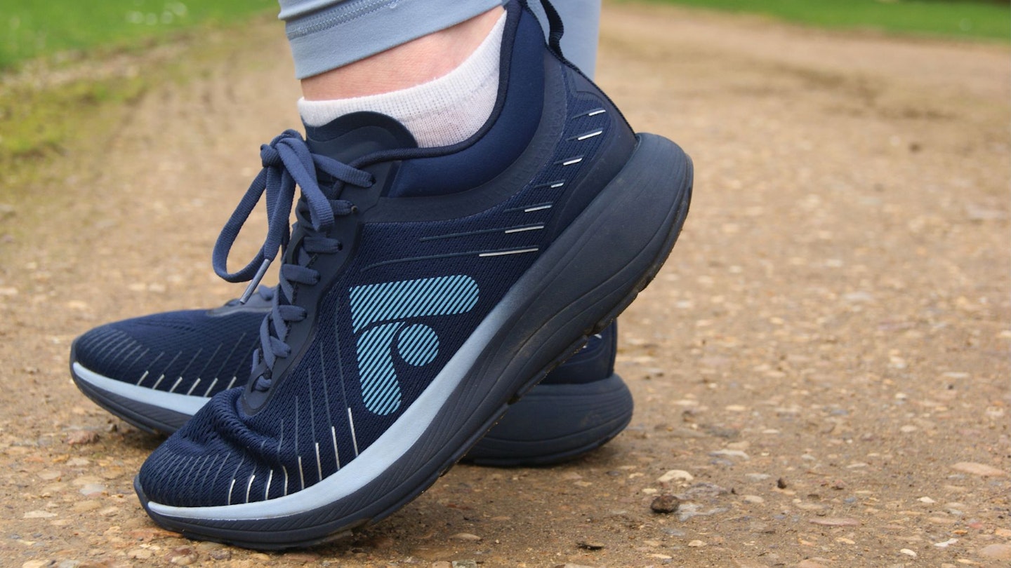 A pair of FitFlop FFRUNNER trainers, worn with blue leggings on gravel