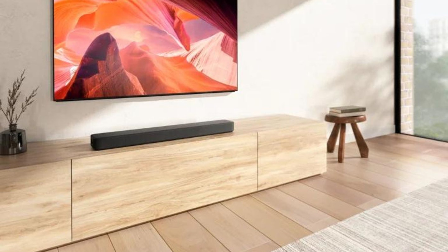 A soundbar sitting on a wooden storage unit underneath a television