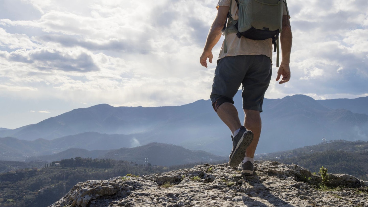 A man wearing a pair of the best walking shorts for men at the top of a mountain
