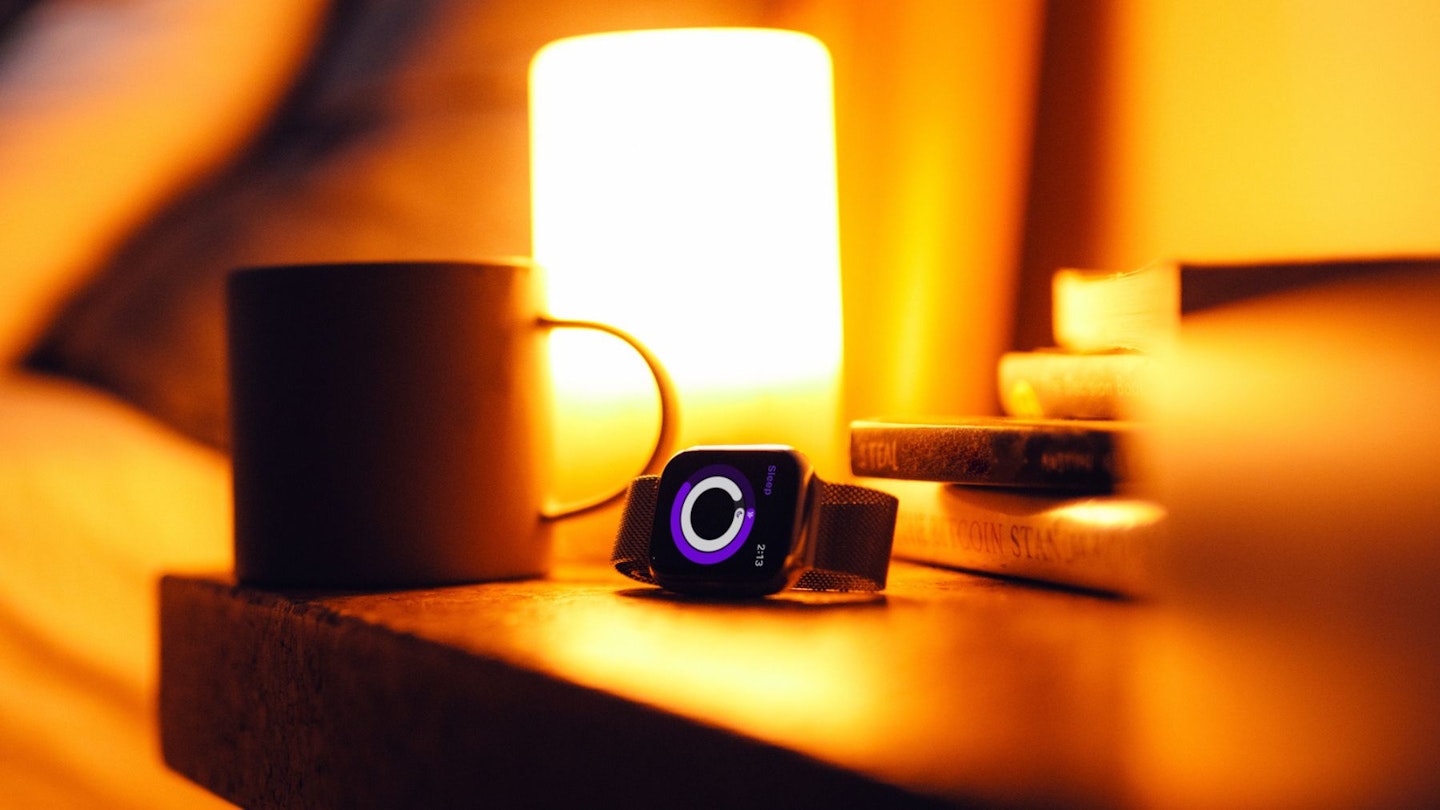 One of the fitness wearables on a bedside cabinet with warm orange light on
